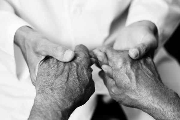 man holding the hands of a senior man