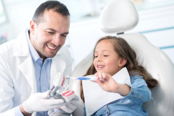 Girl at the dentist learning how to brush her teeth